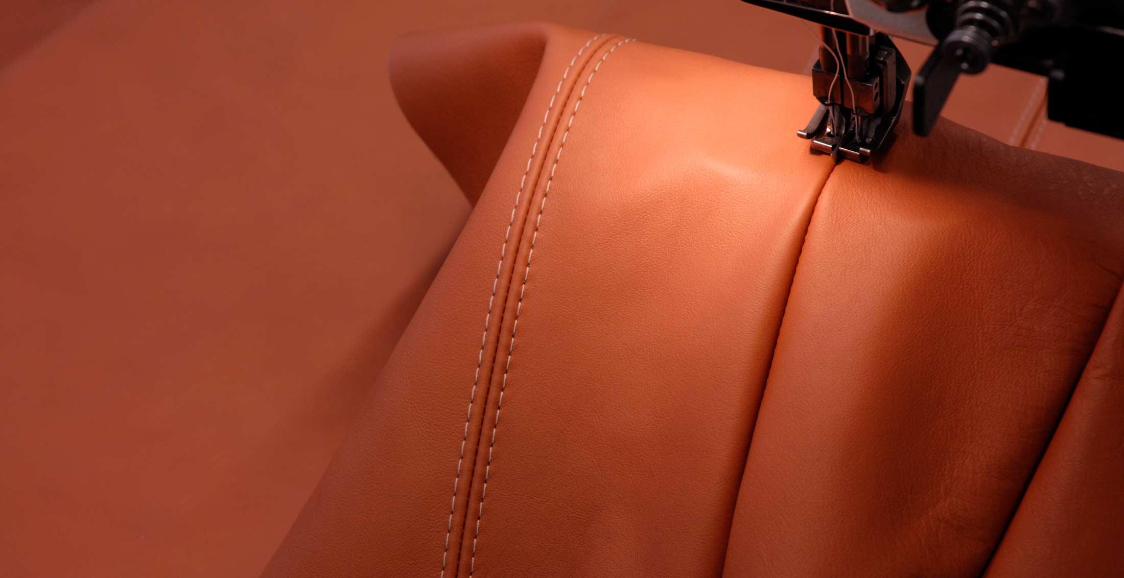 Sewing machine setting a double seam in cognac-coloured leather