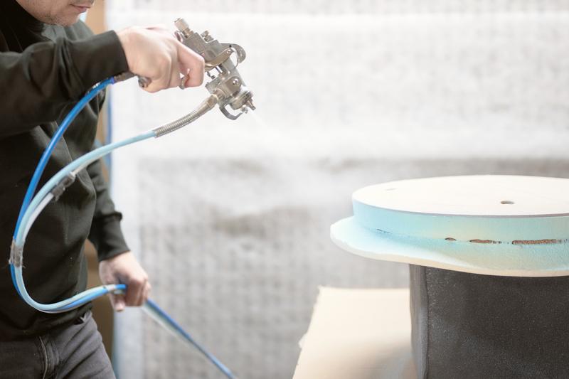 Adhesive being sprayed onto a seat shell
