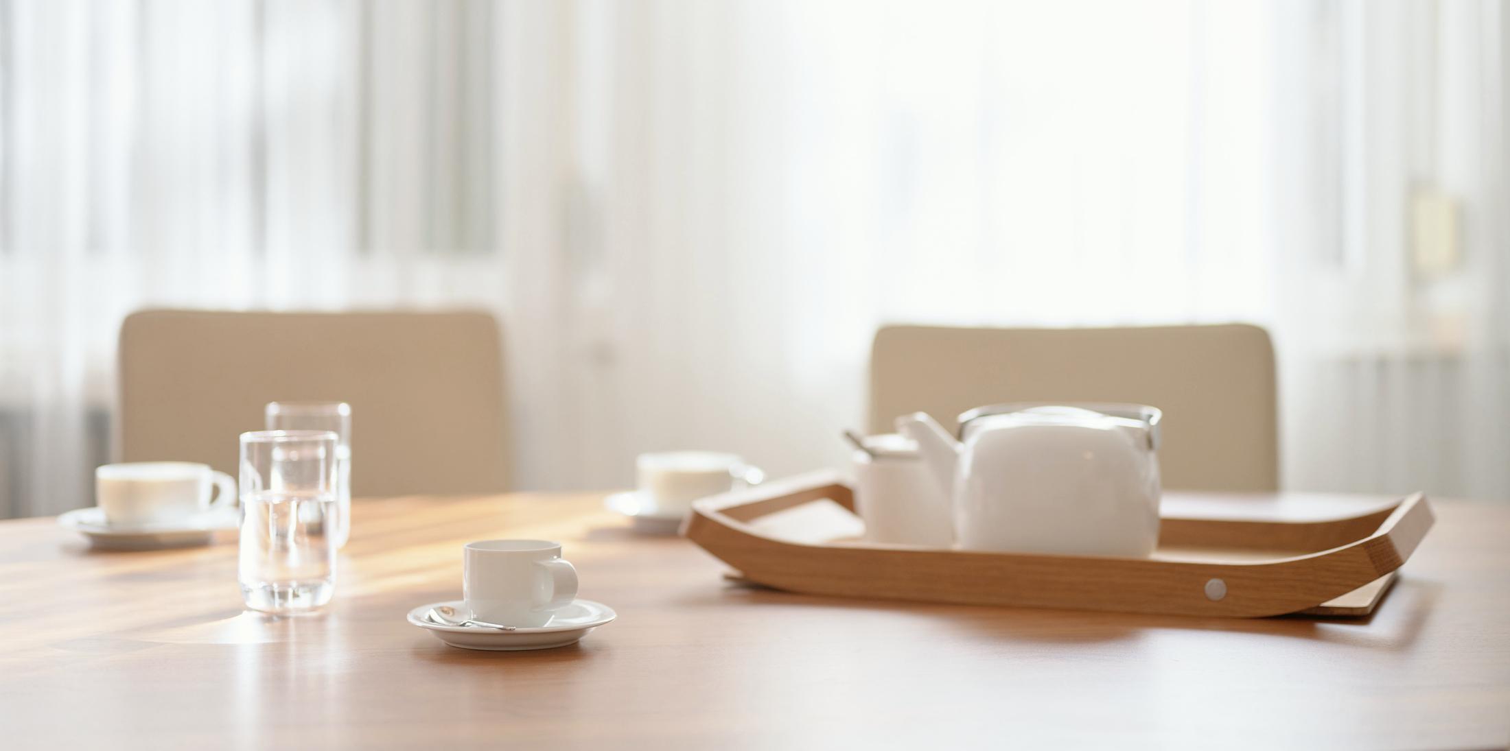 Vergadertafel met theepot en kopjes in het daglicht