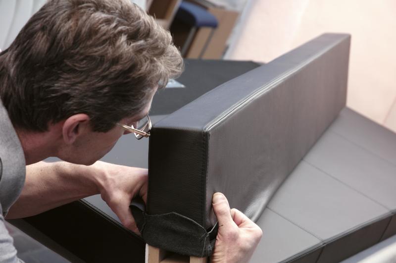 Upholsterer pulling a cover over an upholstered part