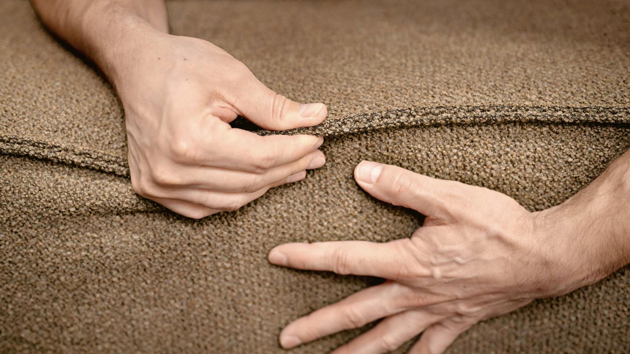 Hands checking the seam of a cushion with a brown cover