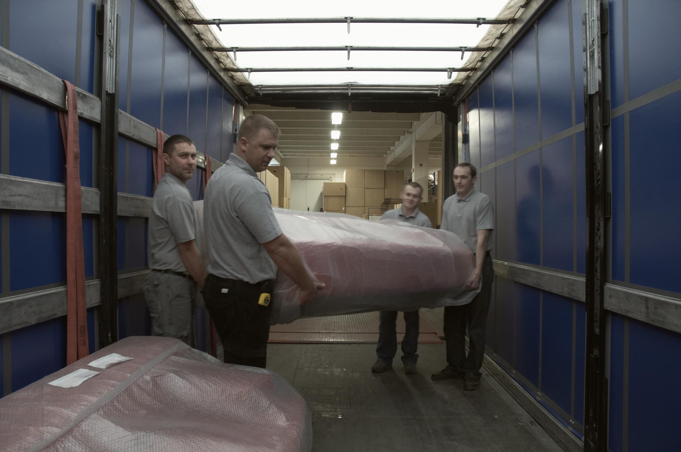 Staff loading a wrapped sofa onto a lorry