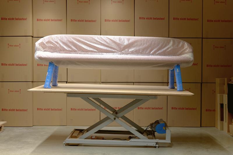 Wrapped bench on a lift table in front of stacked shipping boxes